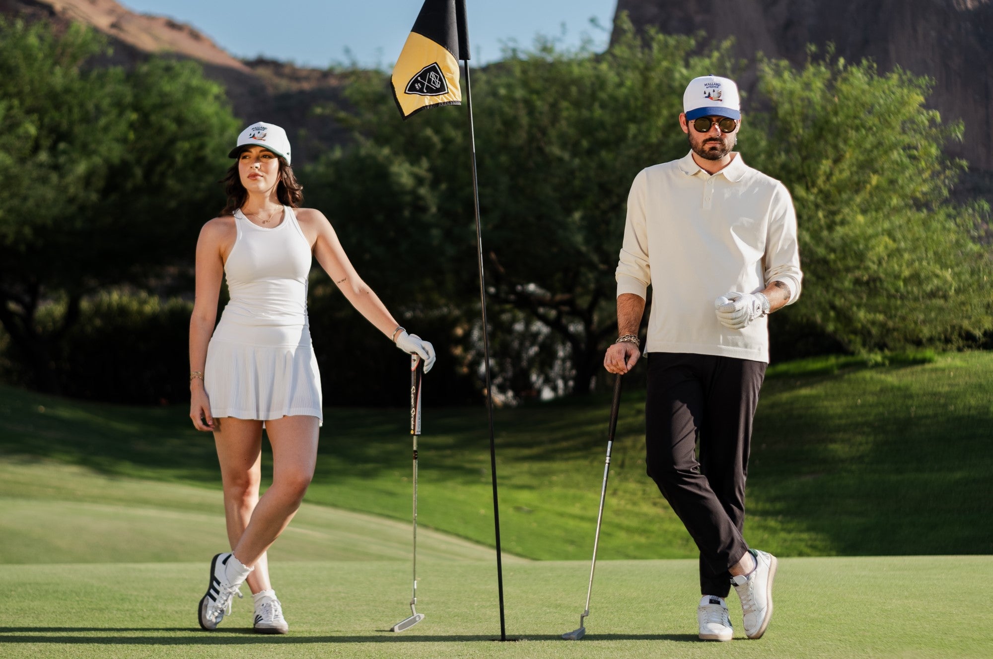 Man and Woman standing next to a golf course flag with Mallard and Friends Premium five Panel Hats