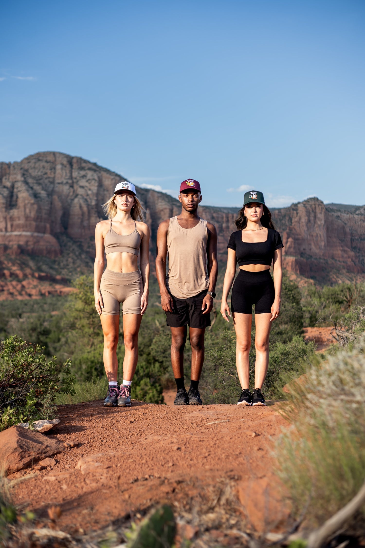 Three friends in sportswear walking through a canyon wearing Mallard and Friends Premium Hats