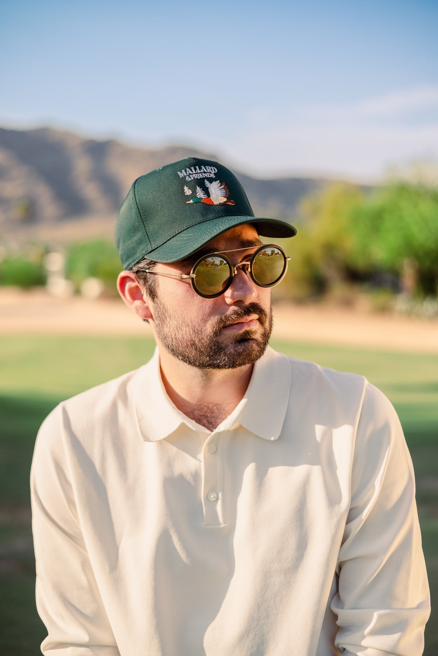 Man with glasses wearing Mallard and Friends Green Five Panel Hat in a golf course