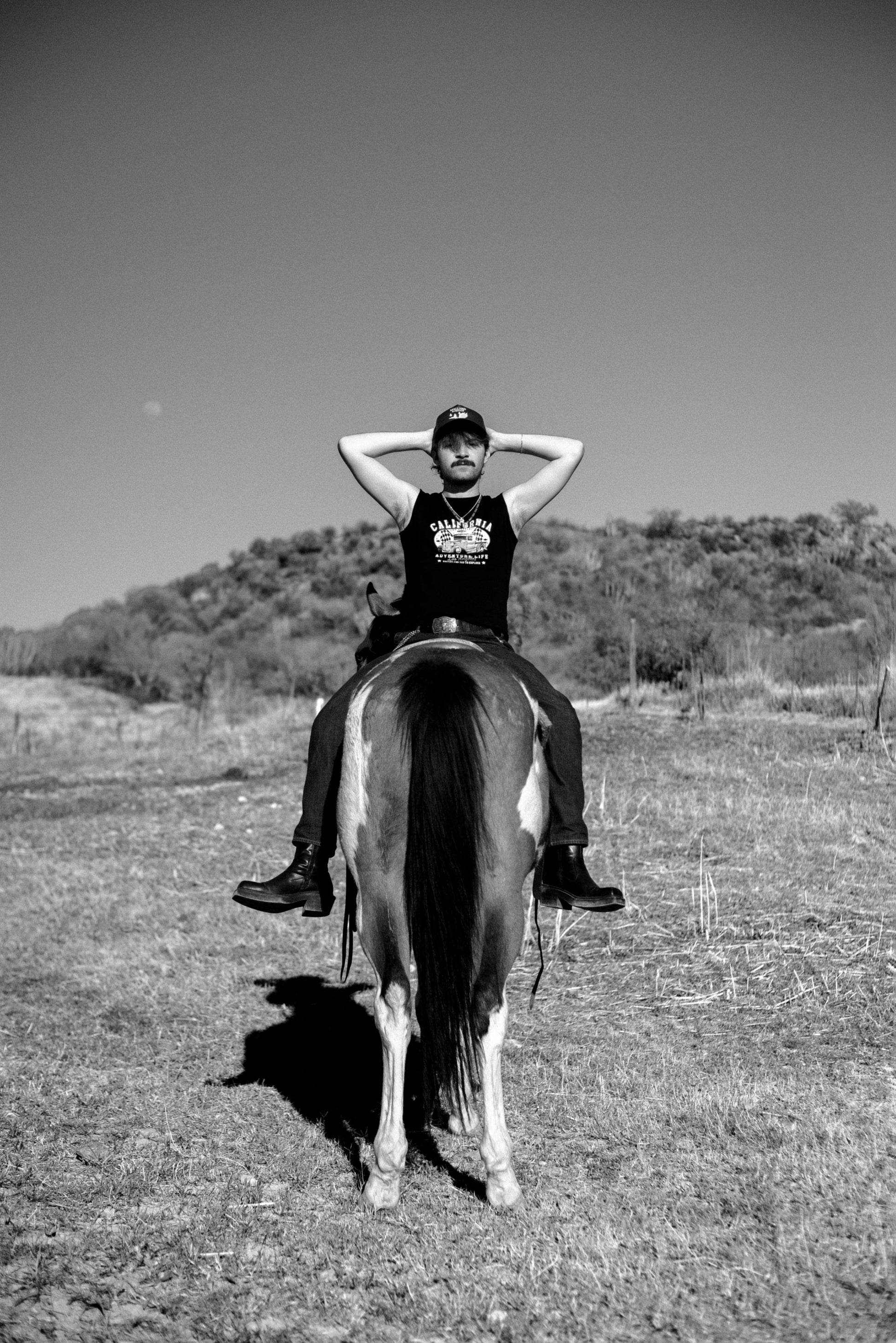 Black and White photo of man in a horse wearing Mallard & Friends Black Five Panel Hat