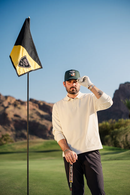 Man standing next to golf hole flag wearing Mallard & Friends Dark Green Five Panel Hat