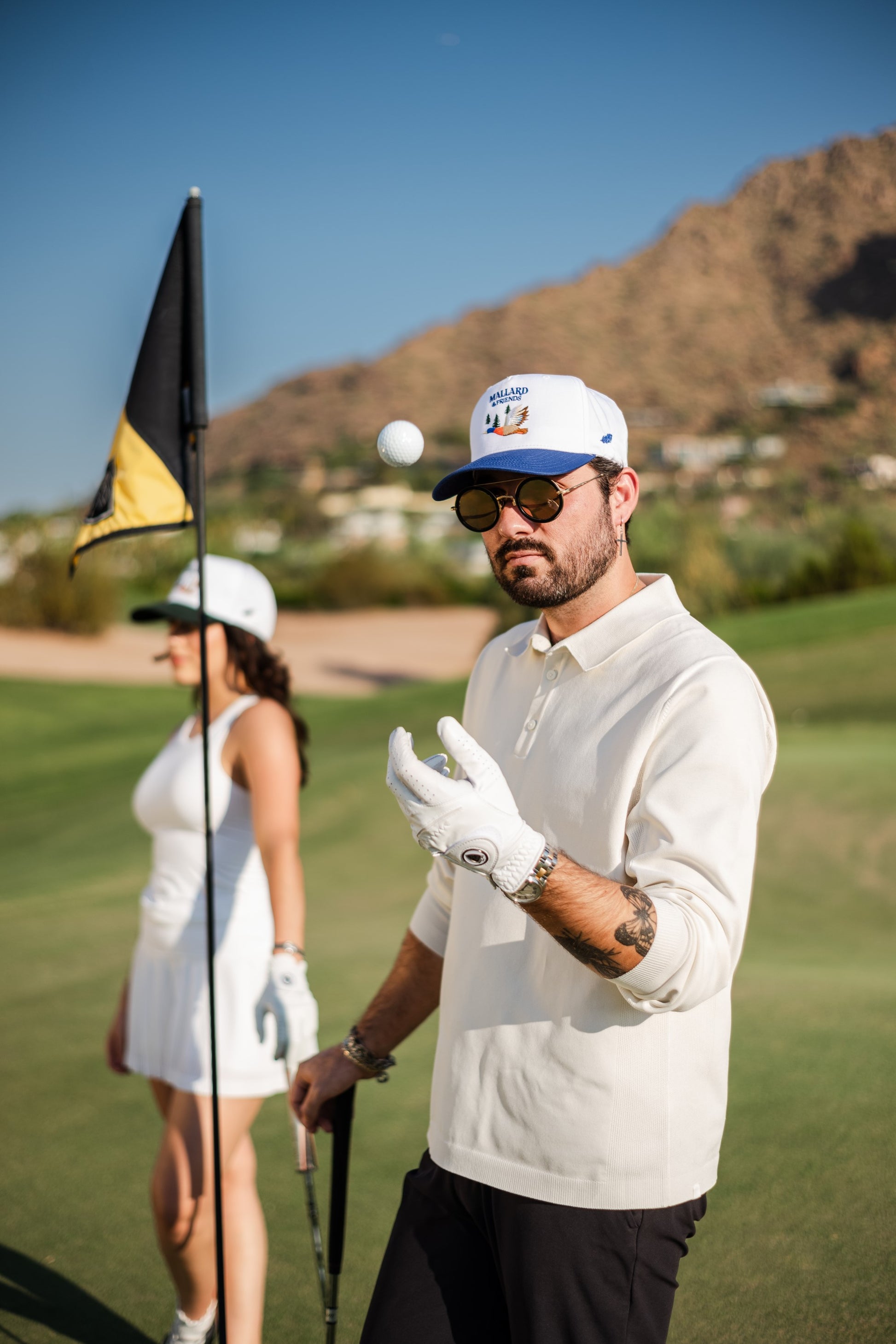 Man and Woman wearing Mallard and Friends Hats with a golf ball in the man's hand